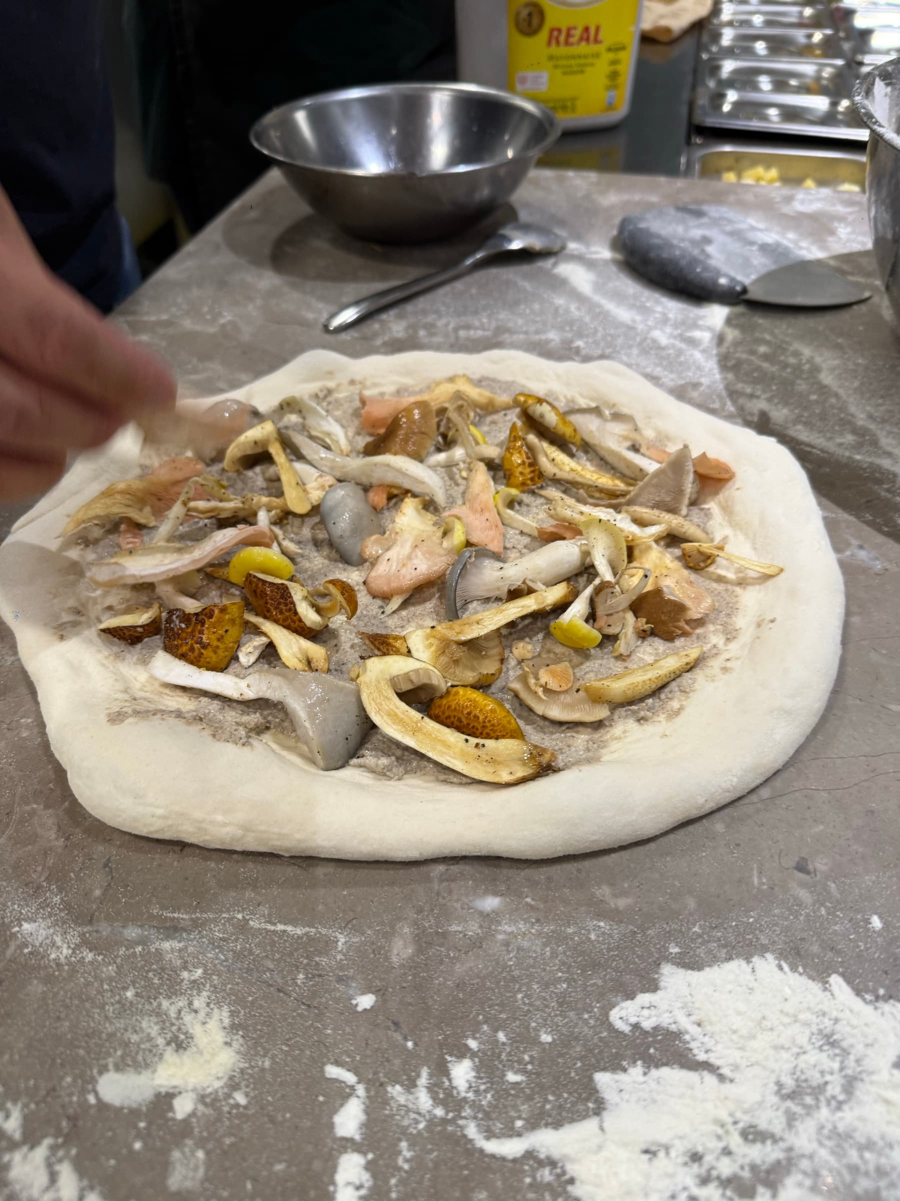 A chef topping a pizza with fresh Shroomy mushrooms